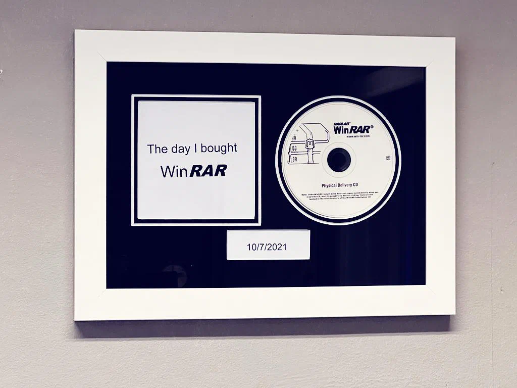 Framed WinRAR disc and license displayed on an office wall